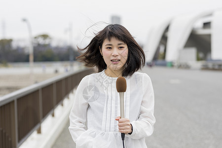 室外台风天播报新闻的年轻女记者图片