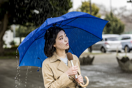 室外撑着伞报道新闻的年轻女性图片