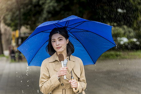 雨伞广告撑着雨伞报道了下雨的街道的女记者背景