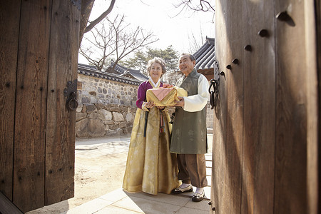 民俗村穿着传统服装拿着礼物盒微笑的夫妇图片