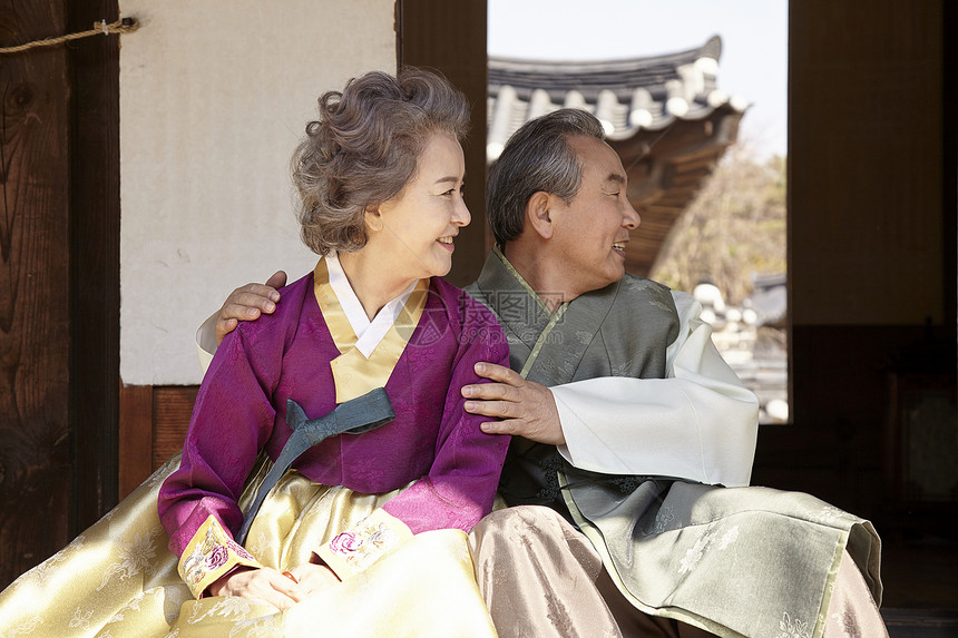 穿着传统服装坐在户外开心的夫妇图片