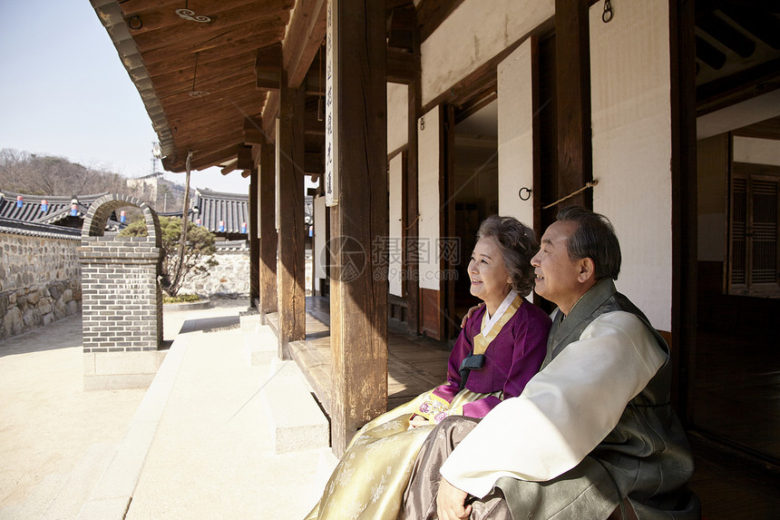穿着传统服装坐在屋外看风景开心的夫妇图片