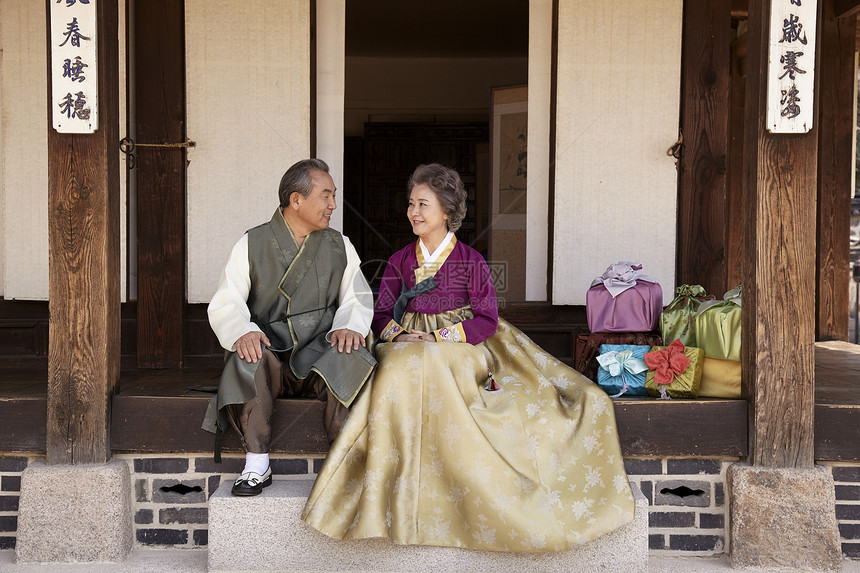 穿着传统服装坐在民俗屋前开心的恩爱夫妇图片