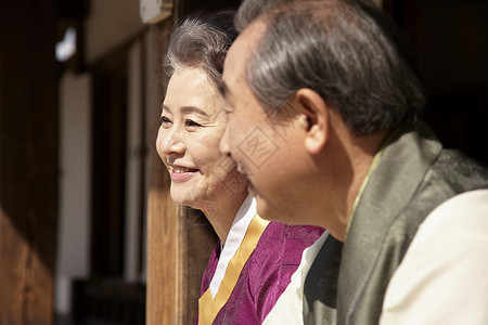 坐在屋外穿着传统服装开心的夫妇背景图片