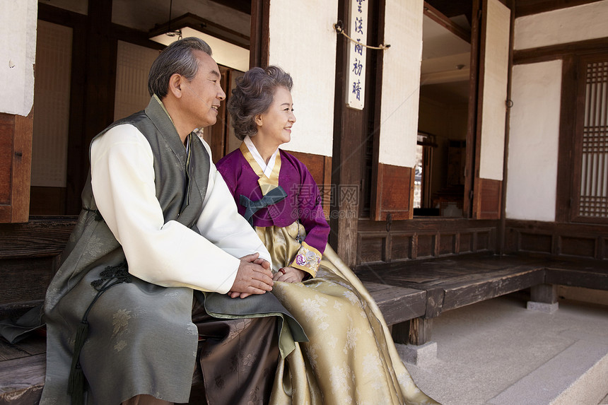 穿着传统服装坐在屋外看风景的夫妇图片