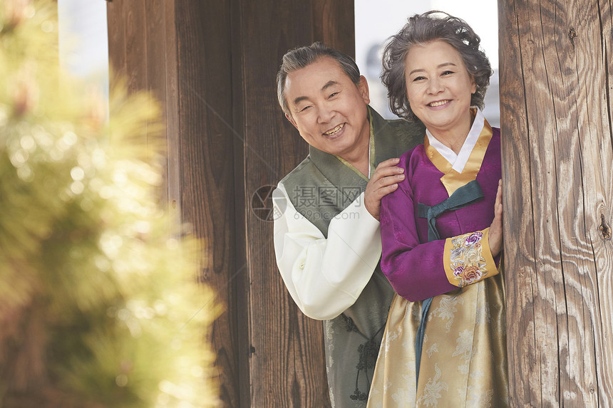 站在柱子后穿着传统服装的老年夫妇图片