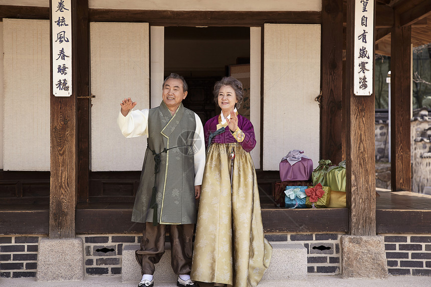 穿着传统服装站在民俗屋前挥手的夫妇图片
