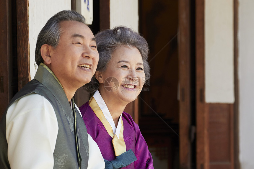 穿着传统服装坐在屋外微笑的夫妇图片