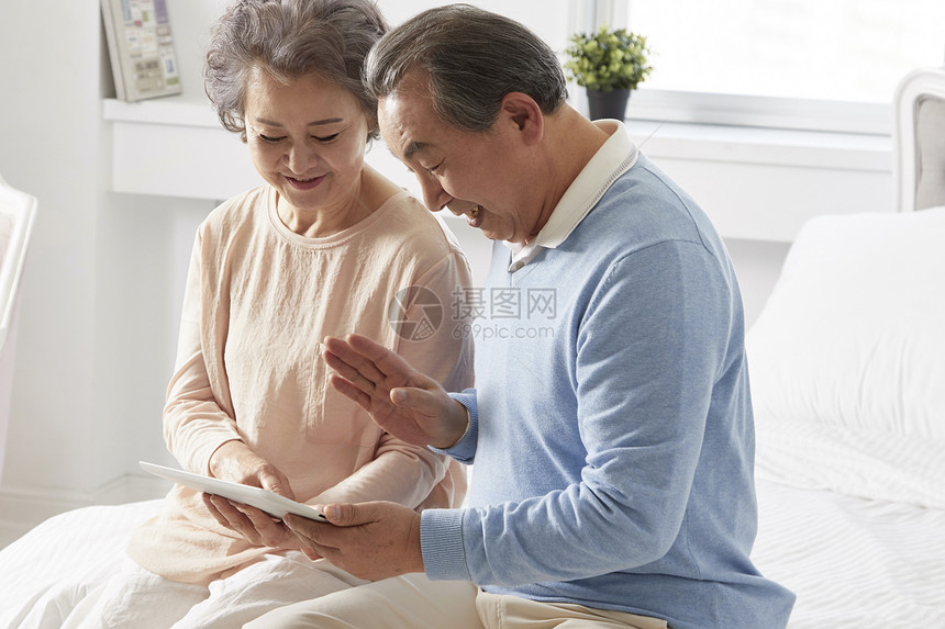 卧室里拿着平板电脑开心的夫妇图片