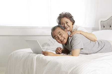 居家床上看笔记本的老年夫妇背景图片