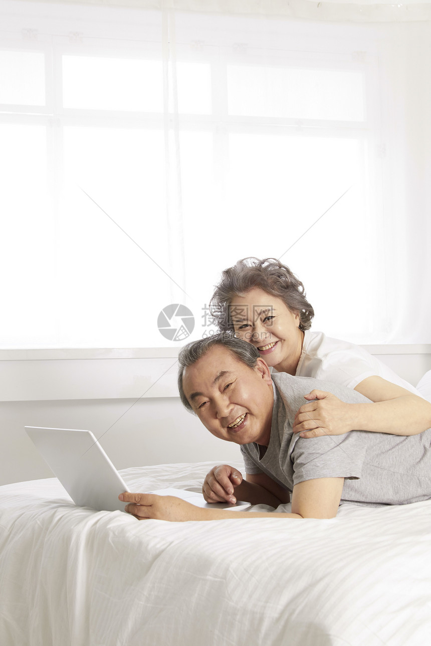 床上看笔记本电脑放松的老年夫妇图片