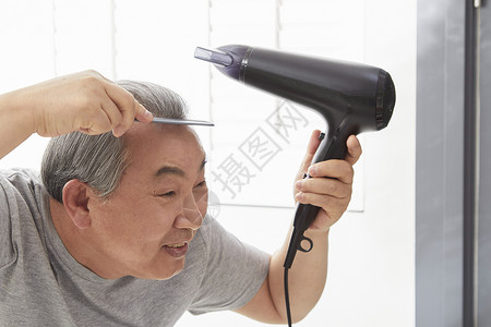 拿着梳子跟吹风机整理发型的老年人图片