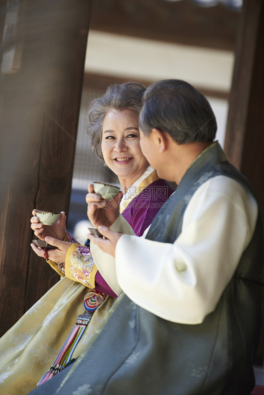 户外穿着传统服装喝茶聊天的老年夫妇图片