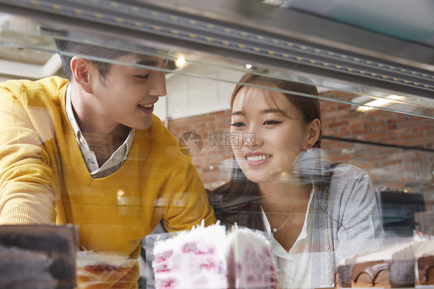 年轻情侣看着咖啡厅橱窗里的甜品图片