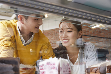 年轻情侣看着咖啡厅橱窗里的甜品图片
