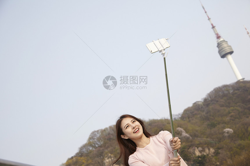 拿着自拍杆自拍的年轻女子图片