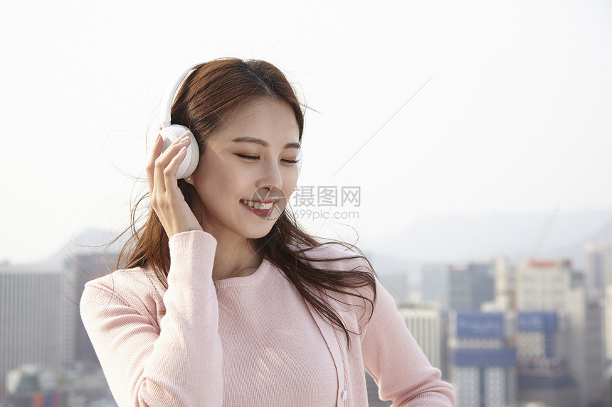 户外戴着耳机放松听音乐的年轻女性图片