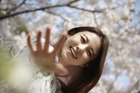 春日站在樱花树下开心的年轻女性图片