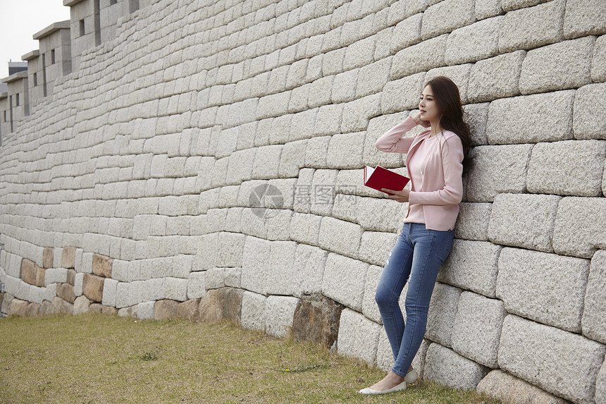 靠在墙上的年轻女性图片