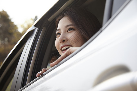 车窗探出头微笑的年轻女性图片