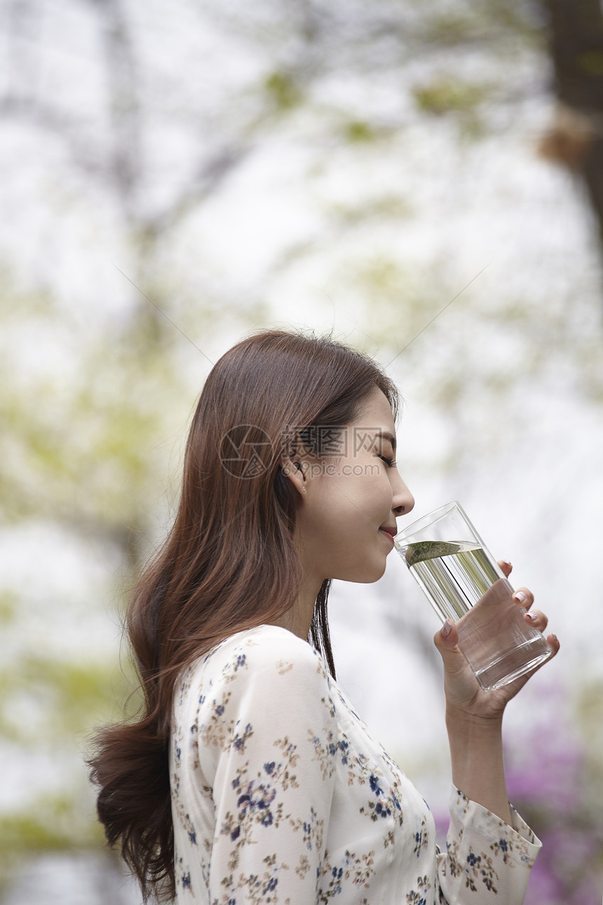 拿着水杯喝水的女青年图片