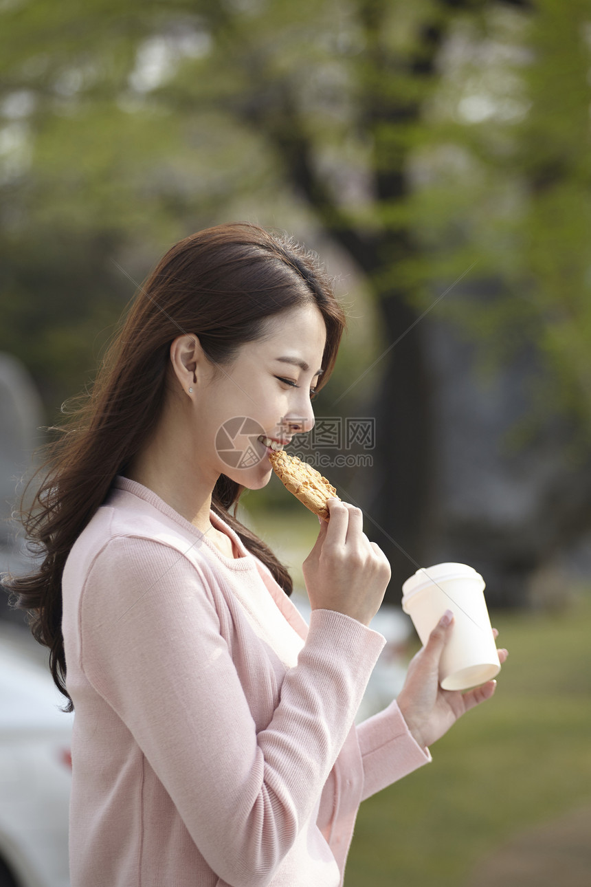 户外吃着饼干的年轻女子图片