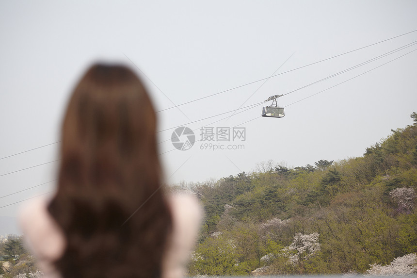 靠在栏杆上看风景的年轻女子背影图片