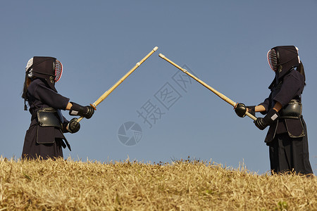 剑指蓝天山丘上穿着剑道服训练的学生背景