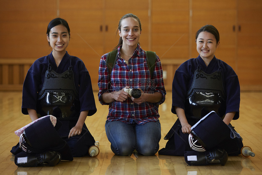 拿着相机的留学少女坐在剑道少女中间图片