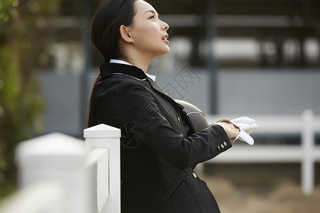 靠着栏杆上拿着头盔的女性图片