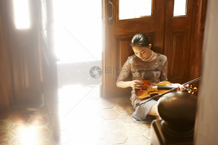 坐在地上拿着小提琴的女性图片