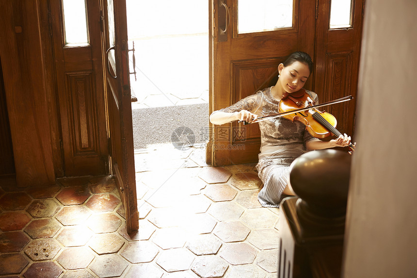 坐在门口拉小提琴的女性图片