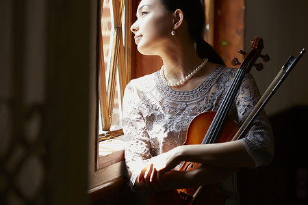 抱着小提琴坐在窗边的成熟女性图片