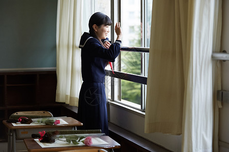 教室里趴在窗户向外看招手的制服女孩图片