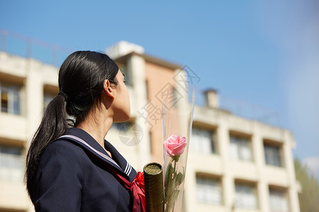 毕业的女学生回望教学楼背景图片