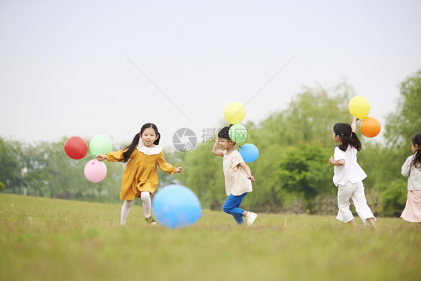 草坪上拿着气球奔跑的孩子们图片
