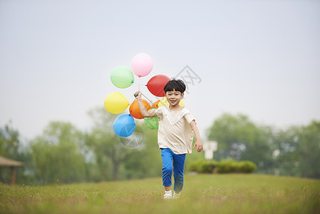 拿着气球开心奔跑的小男孩背景图片