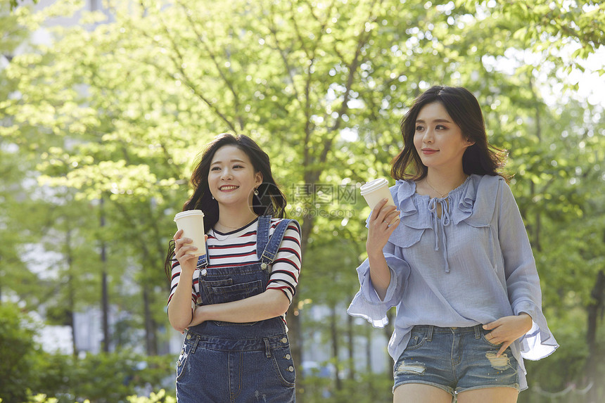 和朋友一起聊天喝咖啡散步的年轻女子图片