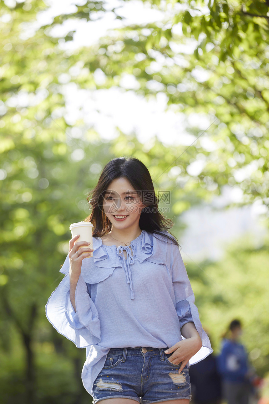 喝咖啡散步的年轻女子图片