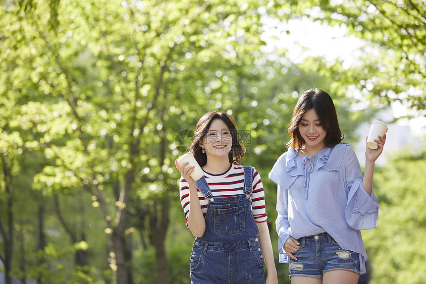 和朋友一起聊天喝咖啡散步的年轻女子图片