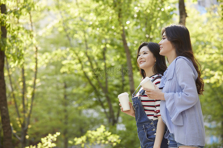 和朋友一起喝咖啡散步的年轻女子图片