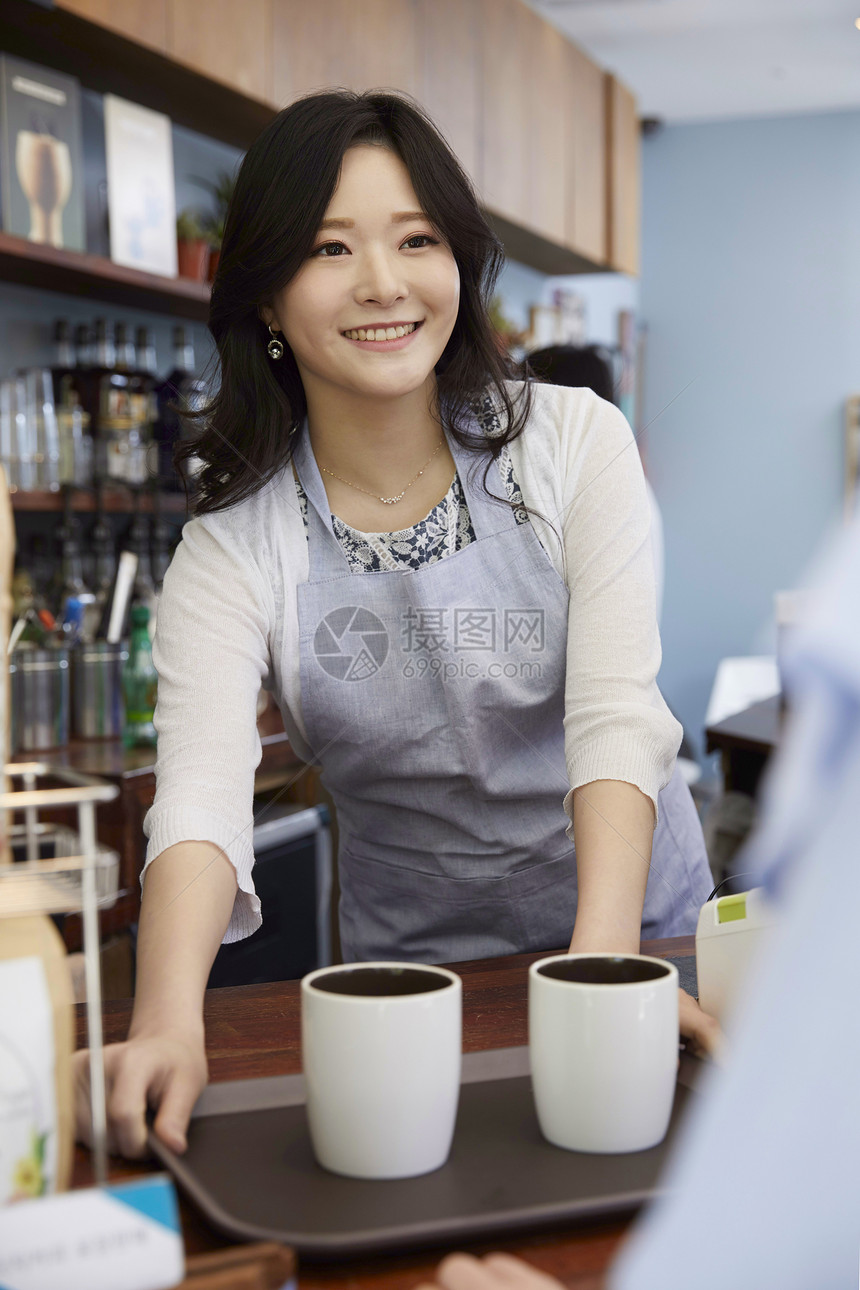 咖啡馆微笑的递出咖啡的年轻女子图片