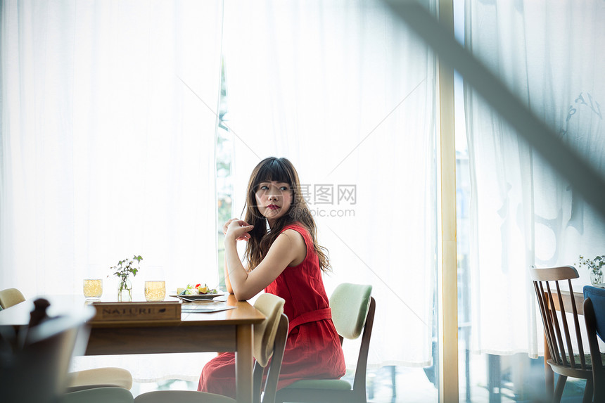 咖啡馆里穿着红裙子的年轻女性图片