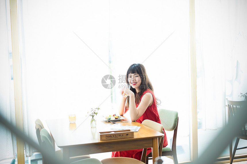 咖啡馆里穿着红裙子微笑的年轻女性图片