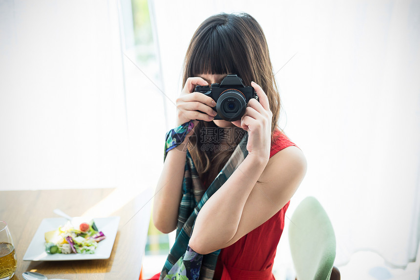咖啡馆拿着相机拍照的年轻女性图片