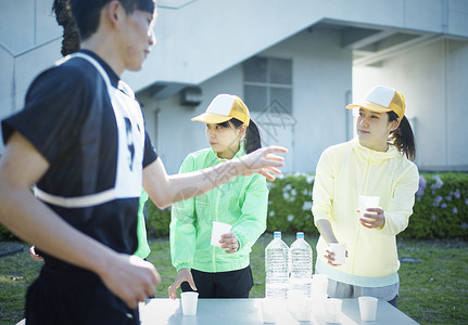 马拉松比赛供水站拿着水杯倒入志愿者图片