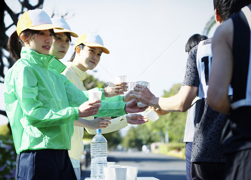 马拉松比赛供水站拿着水杯的志愿者图片
