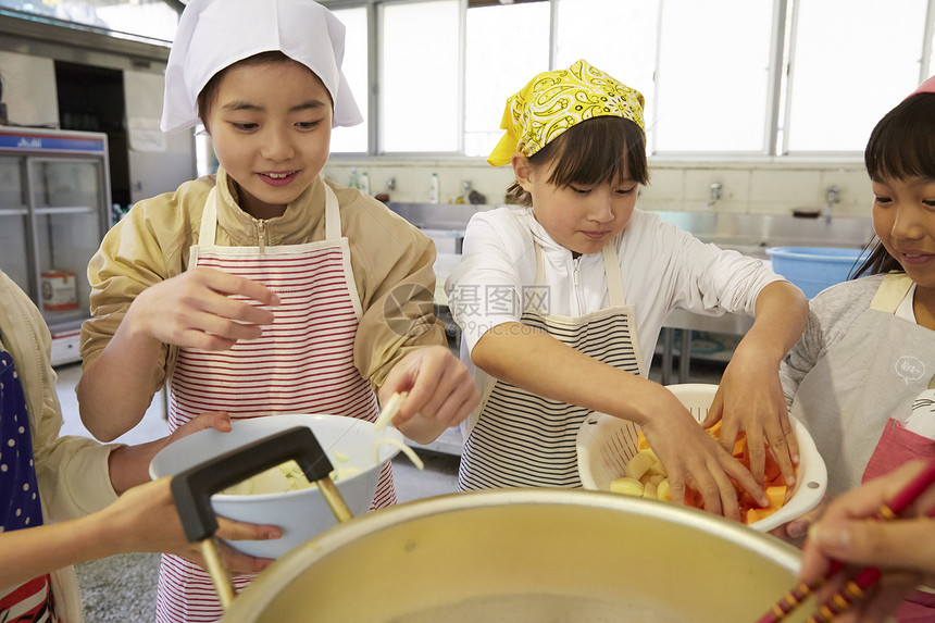 将食材放入大锅烹饪的姑娘们图片