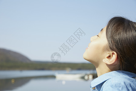 湖边闭眼放松的小女孩图片