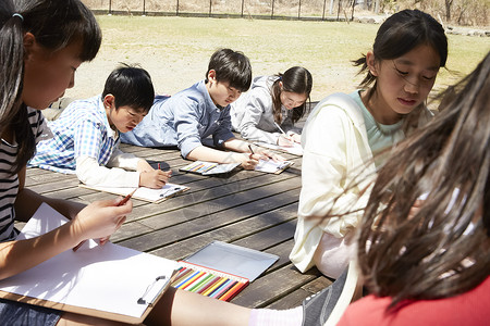 小学生趴在公园的地上写生图片